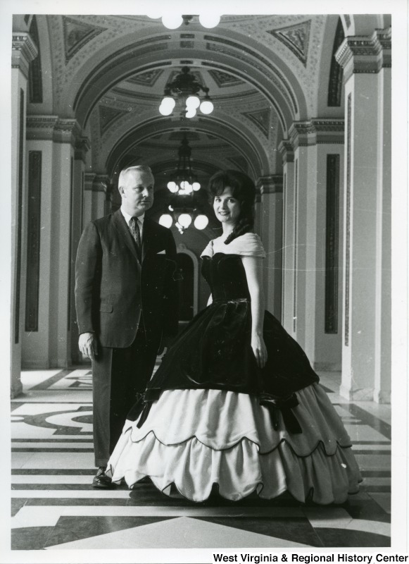 Congressman Arch Moore, Jr. with a woman identified as either Genevive de Beaucorps or Aline Petershchmitt, who is wearing a ball gown.