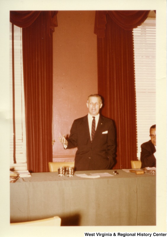 Congressman Arch Moore, Jr. standing behind a table talking.