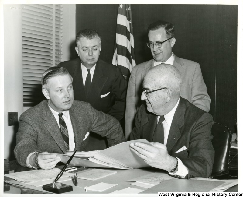 The Lincoln Homes Public Housing Project in Wheeling received Federal approval, as a result of a conference arranged by Congressman Arch A. Moore, Jr., with Public Housing officials. Shown in the photograph seated with Congressman Moore is Mr. R. M. Little, Regional Director of the Public Housing Administration, and standing are Mr. Casey Ireland, Special Assistant to the Housing Commission, and Mr. Russell C. Mozena, Executive Secretary of the Wheeling Housing Authority.