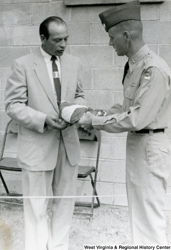 An unidentified man taking an item (possibly a flag) from a member of the Air Force during the Ida May dedication.