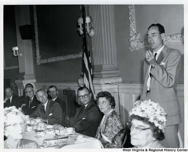 Congressman Arch A. Moore, Jr. seated fifth from the left, listening to an unidentified man give a speech.