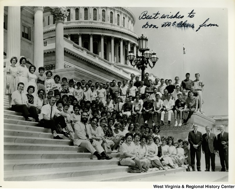 Congressman Arch A. Moore, Jr. with a large unidentified group on the steps of the Capitol Building.  The photo is signed, but the writing is smudged. It reads, "Best wishes to Don ???? from"