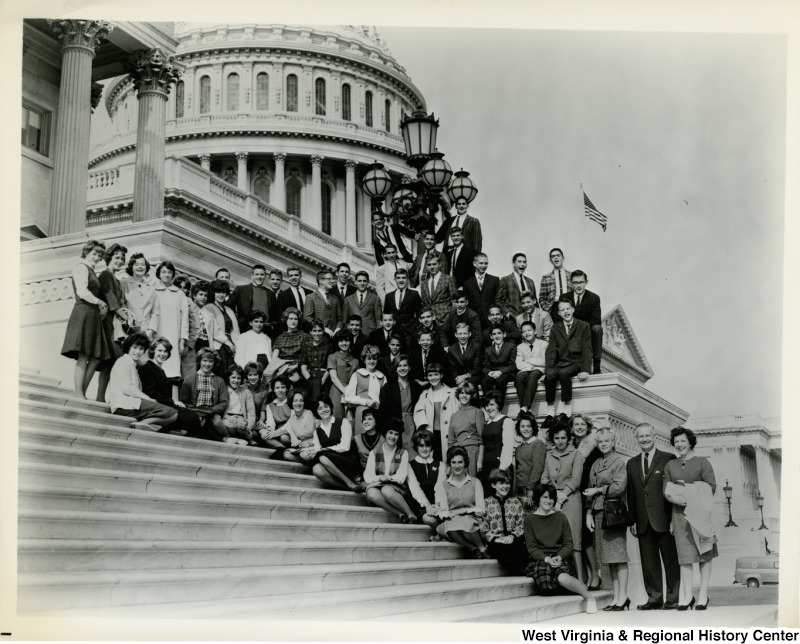 Congressman Arch A. Moore, Jr. with his wife Shelley and a large unidentified group on the steps of the Capitol Building.