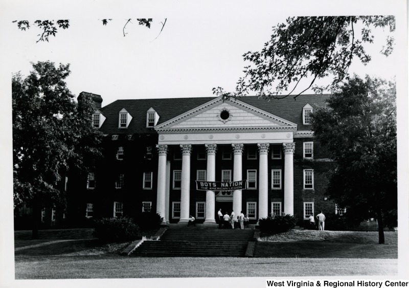 A building with a banner stating, "Boys Nation The American Legion." A group of young men are sitting or standing on the steps.