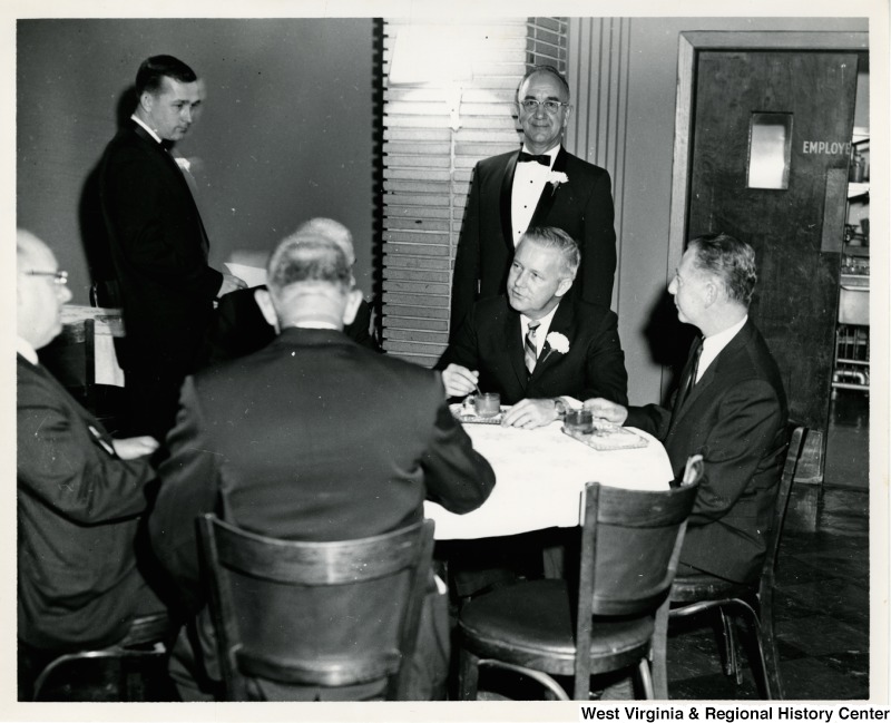 Congressman Arch A. Moore, Jr. sitting at a table with four unidentified men having a conversation during the Elks Memorial Service.