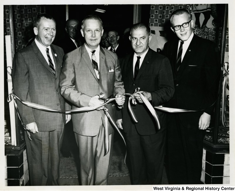 Congressman Arch A. Moore, Jr. getting ready to cut a ribbon at a re-election campaign event. Three other unidentified men are standing beside him.