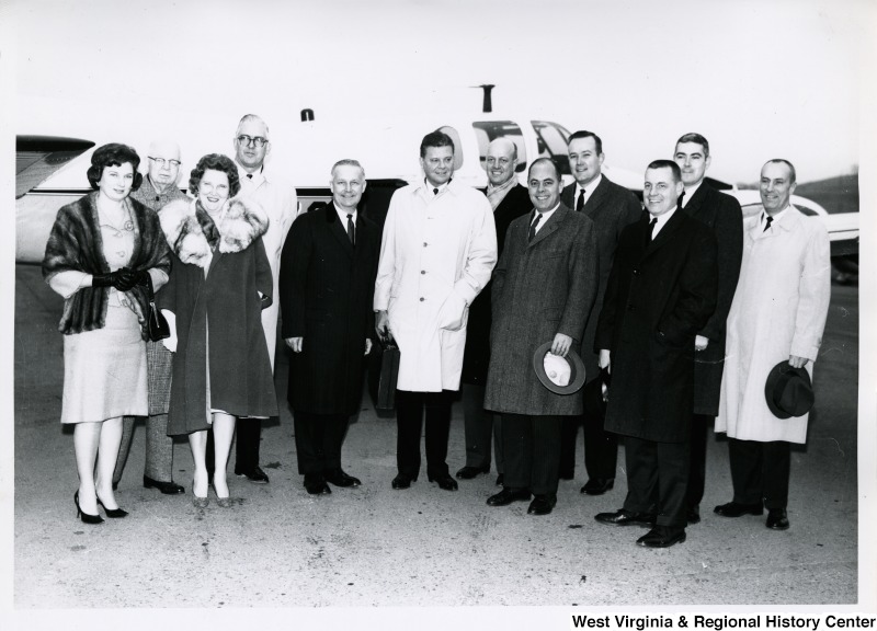 Congressman Arch A. Moore, Jr. (left of center) with a small group of people in front of a plane. His wife, Shelley, is the first person on the left, front.