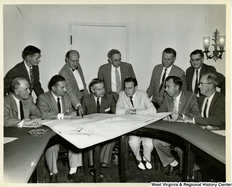 Congressman Arch A. Moore, Jr. going over a map with a group of unidentified men.