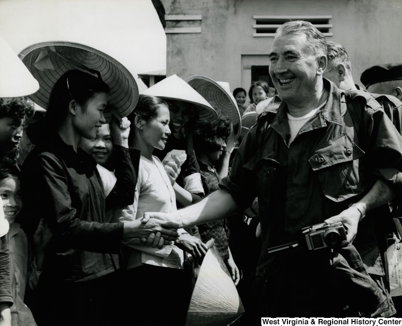 An unidentified man in uniform is shaking the hand of an unidentified Vietnamese woman in the Cau Xa Village.