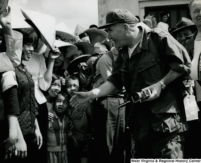 An unidentified man in uniform is reaching out to shake the hand of an unidentified Vietnamese woman in the Cau Xa Villiage.