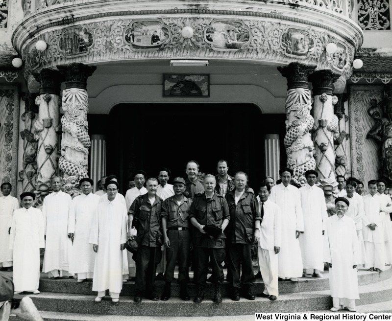 Congressman Arch A. Moore, Jr standing in front of the Cao Dai Temple in Tay Ninh, Vietnam with military personnel and temple workers.