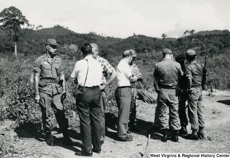 Eight unidentified men standing in groups talking in the Kon Tum Province, Vietnam.