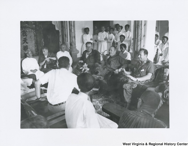 An unidentified group of men sitting and talking in Vietnam. Some men are standing in the background listening to the conversation.