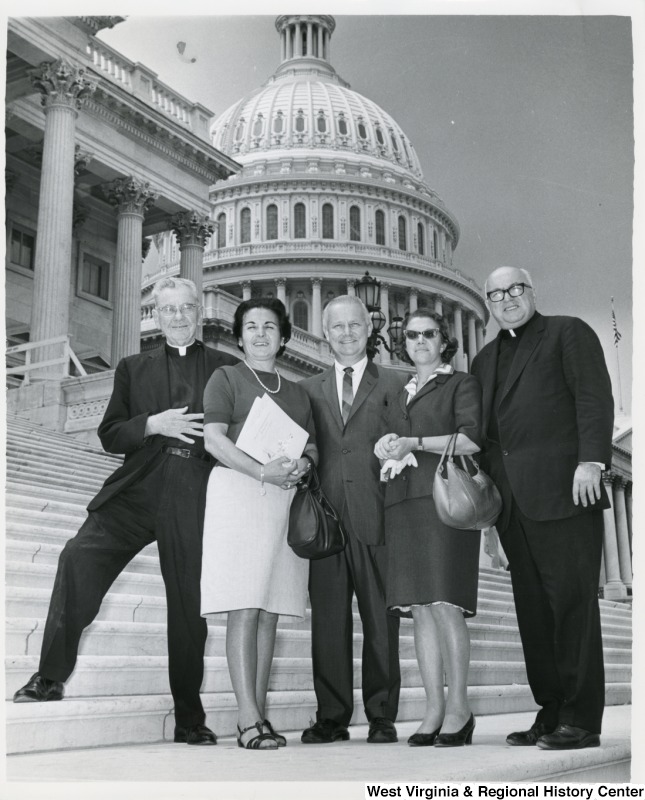 Congressman Arch A. Moore, Jr. (center) standing on the steps of the Capitol with four unidentified people. The men are priests.