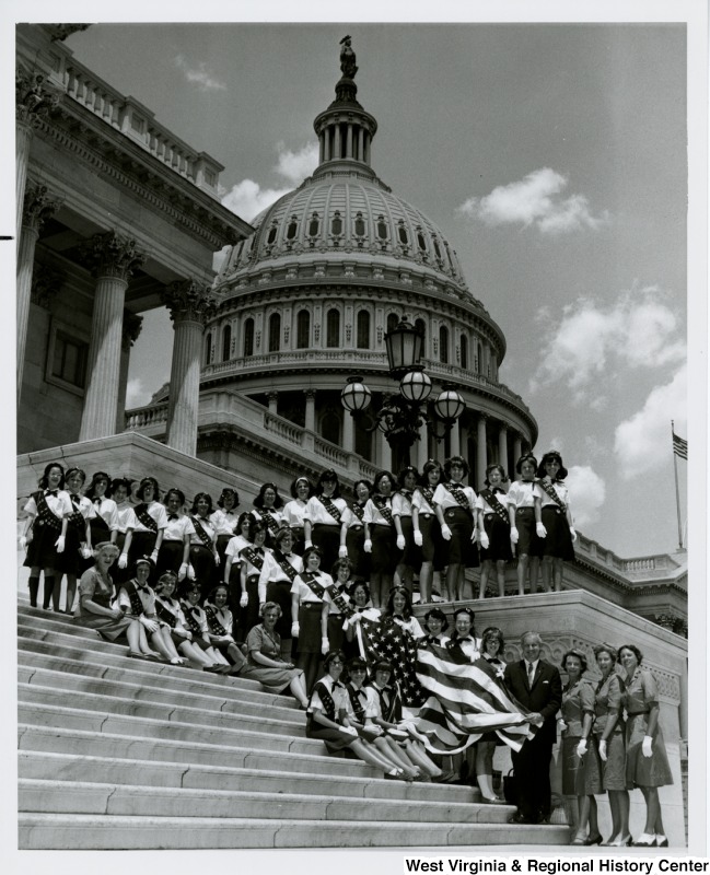 Congressman Arch A. Moore, Jr. on the steps of the Capitol with the Wheeling Girl Scout Troop. Moore is holding the American flag with five Girl Scouts.