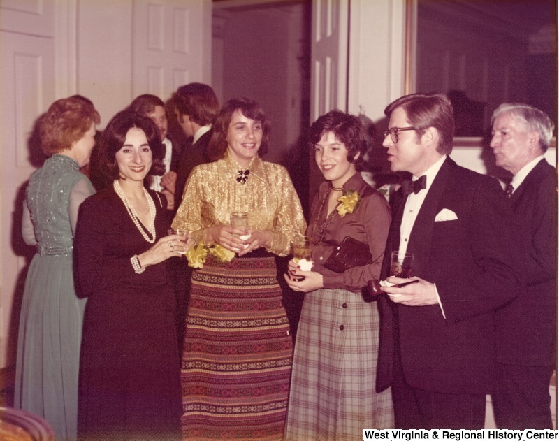 Three unidentified women and two men having a conversation at a reception.