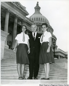 Congressman Arch Moore, Jr. with two unidentified women in uniforms standing on the steps of the Capitol Building.