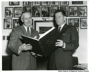 Congressman Arch Moore, Jr. looking at a large book with an unidentified man.