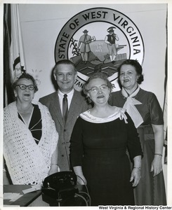 Congressman Arch A. Moore, Jr. standing with three unidentified women. The West Virginia Seal is in the background.