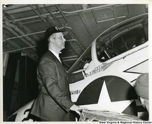 Congressman Arch A. Moore, Jr. standing on a stool inspecting an airplane on board the U.S.S. Franklin D. Roosevelt.