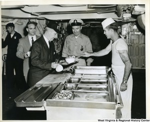 Congressman Arch A. Moore, Jr. being served food on board the U.S.S. Franklin D. Roosevelt.  Two unidentified people are also waiting to be served food.