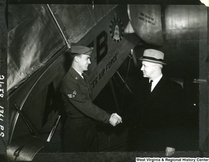 Airman Marion L. Mussili shaking hands with Congressman Arch A. Moore, Jr.  immediately after their arrival at MATS (Military Air Transport Service) terminal, Andrews AFB (Air Force Base), Maryland from Europe. Congressman Moore interceded in the confinement of Airman Mussili by the Greek Government after his conviction for hitting a pedestrian with a military vehicle. Moore then brought the airman back to the states with him.