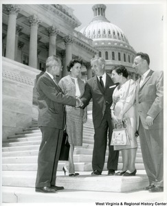 Congressman Arch A. Moore, Jr. shaking hands with an unidentified man on the steps of the Capitol Building. Two unidentified women and a man are standing with him.