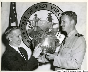 Congressman Arch A. Moore, Jr. and an unidentified military officer holding a silver bowl, which was given by the citizens of Wheeling to the officer's mess on the U.S. gunboat "Wheeling" in September 1897.