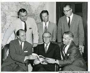 Congressman Arch A. Moore, Jr. (seated, right), Congressman William M. McCulloch (center), and four others looking at the book Congressional and Administrative News.