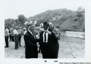 Congressman Arch A. Moore, Jr. shaking the hand of an unidentified Fairmont (W.Va.) veteran while he is being hugged from behind by an unidentified man.  They are all laughing.