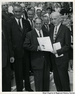 General of the Army Douglas MacArthur receives from the House Speaker John McCormack a certificate of appreciation authorized by Congress. At left is Vice President Lyndon Johnson.