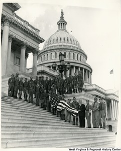 Congressman Arch A. Moore, Jr. standing on the steps of the Capitol with a group of Boy Scouts from Troop 10. Some of the Boys Scouts are holding a American Flag.
