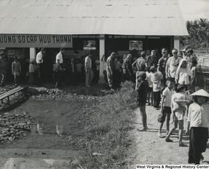 A group of people standing around a building in the Cai Be refugee camp, Vietnam.