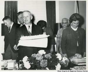 Congressman Arch A. Moore, Jr. holding his birthday cake. His wife, Shelley, is standing beside him.