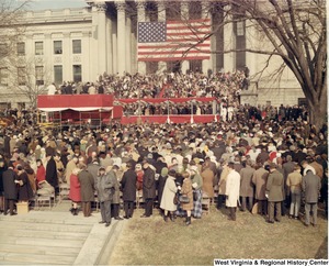 A large crowd gathered in front of a raised stand for Governor Arch Moores swearing in ceremony.