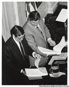 Two unidentified men are looking through a thick stack of documents during Governor Moore's State of State address.
