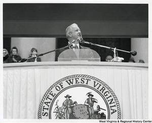 Governor Arch Moore speaking at a podium featuring the Great Seal of West Virginia.