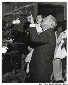 Governor Arch Moore holding an orphan little girl and showing her the Christmas tree in the Governors mansion.