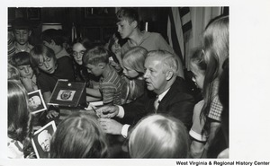 Governor Arch Moore signing photographs for an unidentified group of kids.