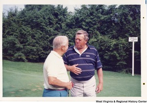 Governor Arch Moore talking to an unidentified man while golfing.