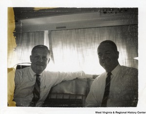 Governor Arch Moore and an unidentified man on a flight with Cathay Pacific Airways. The photograph has some damage on the left side.