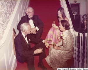 Two unidentified men and two unidentified women sitting on some steps at a reception.