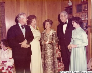 Two unidentified men and three unidentified women talking at a reception.