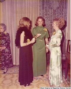 Three unidentified women talking at a reception.