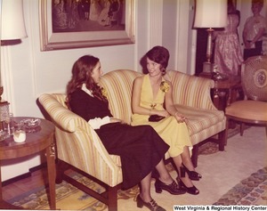 Two unidentified women sitting on a couch talking during reception.