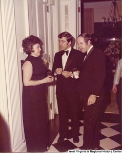 Two unidentified men speaking to an unidentified woman at a reception.