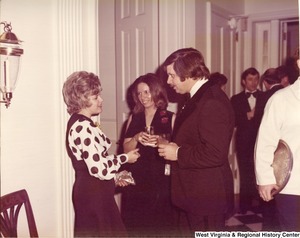 An unidentified man speaking to two unidentified women at a reception.