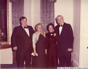 Two men and two women posing for a photograph during a reception.