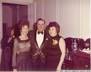 An unidentified man with two women posing for a photograph during a reception.