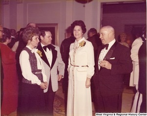 Two men and two women talking at a reception.